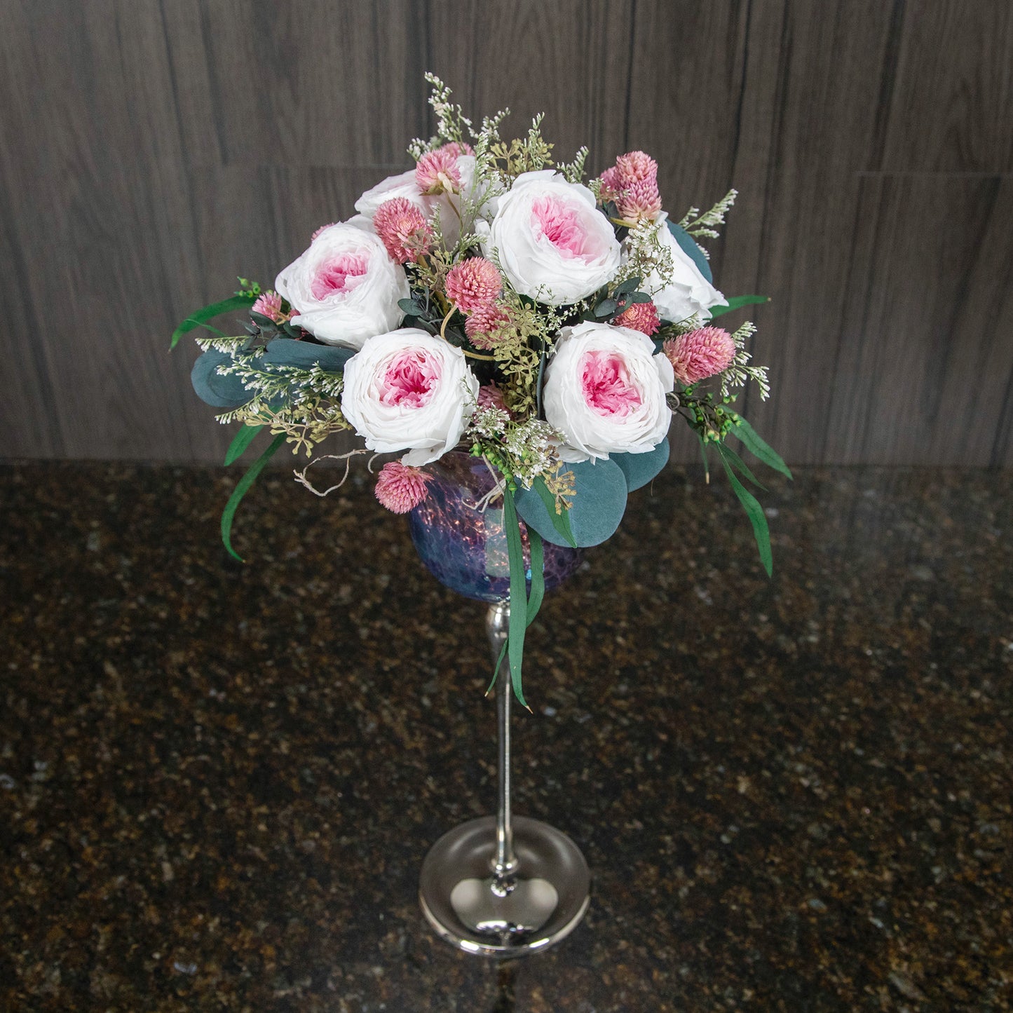 top down view of pink preserved garden roses in a tall stemmed glass vase