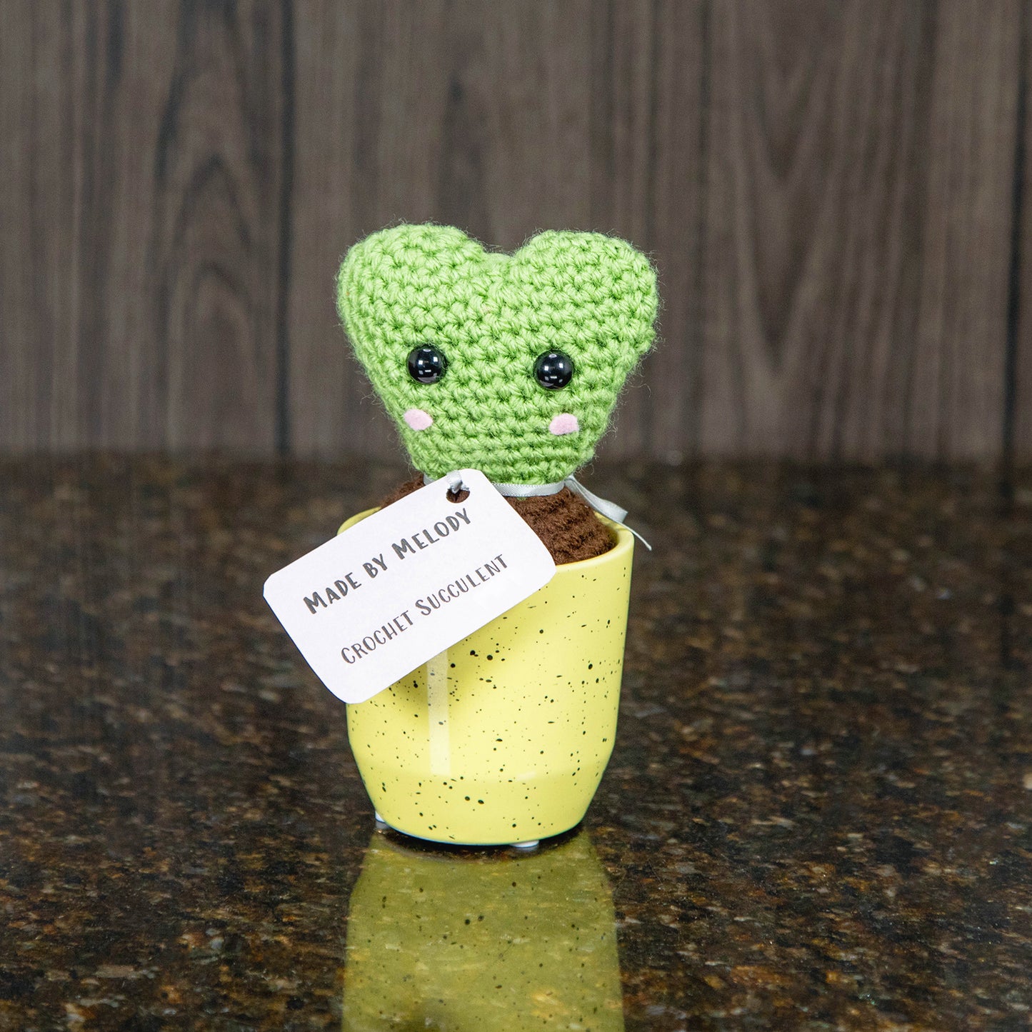 a crochet hoya succulent with a cute cartoonish face in a yellow ceramic pot