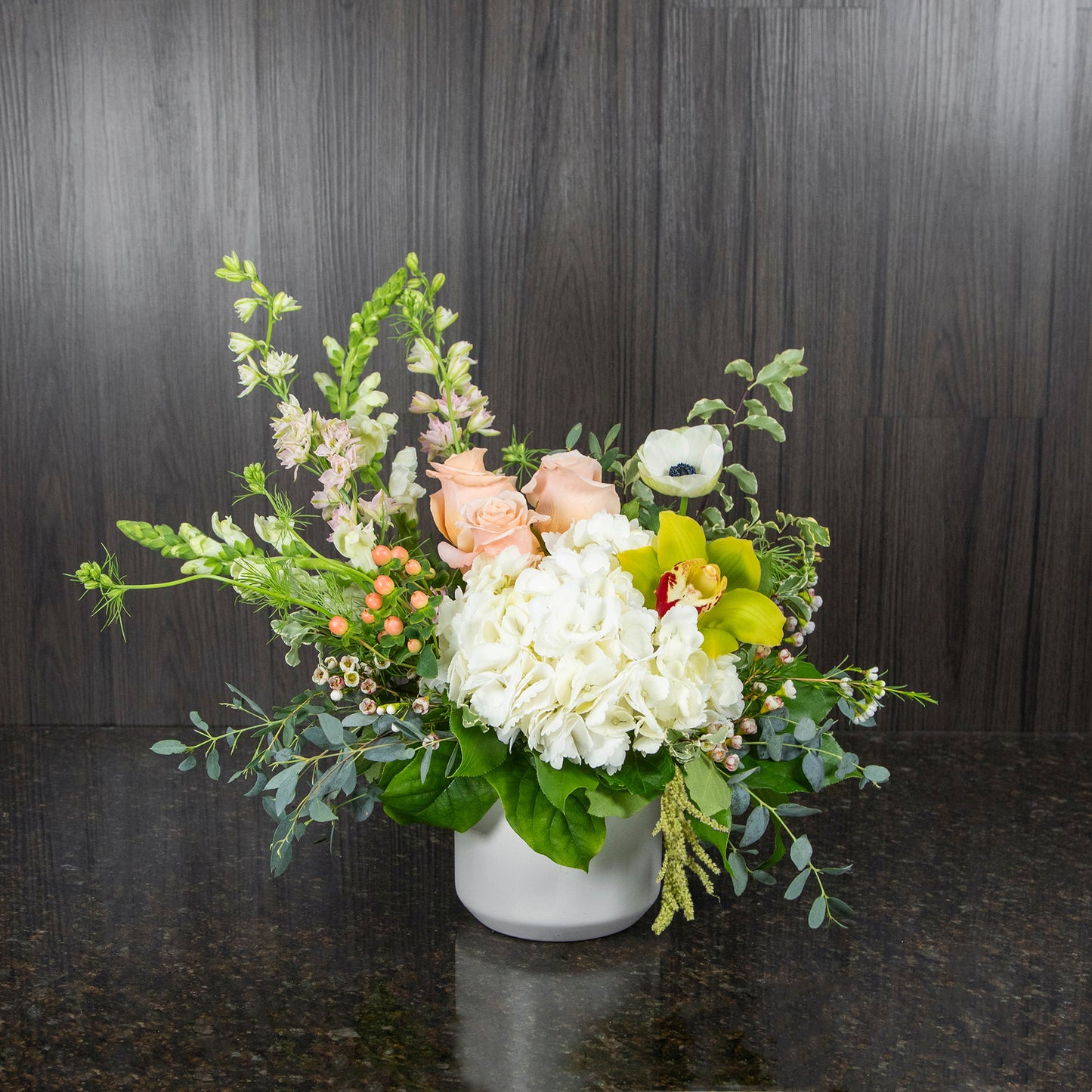a mix of pastel flowers in a white ceramic pot