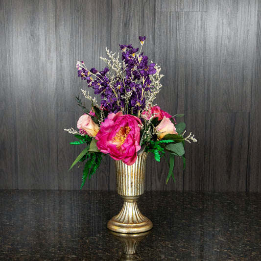 colorful dried flowers, filler, and dried greenery in a gold footed metal vase