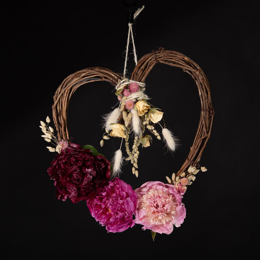 a dried heart shaped floral wreath with big pink dried peonies
