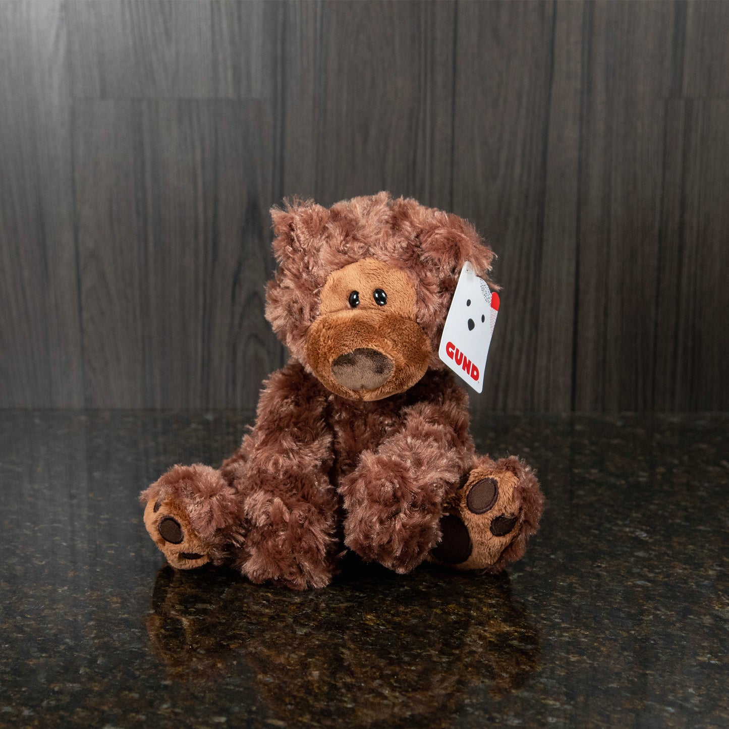 a chocolate brown teddy bear with a big nose and eyes that are intentionally a little lopsided