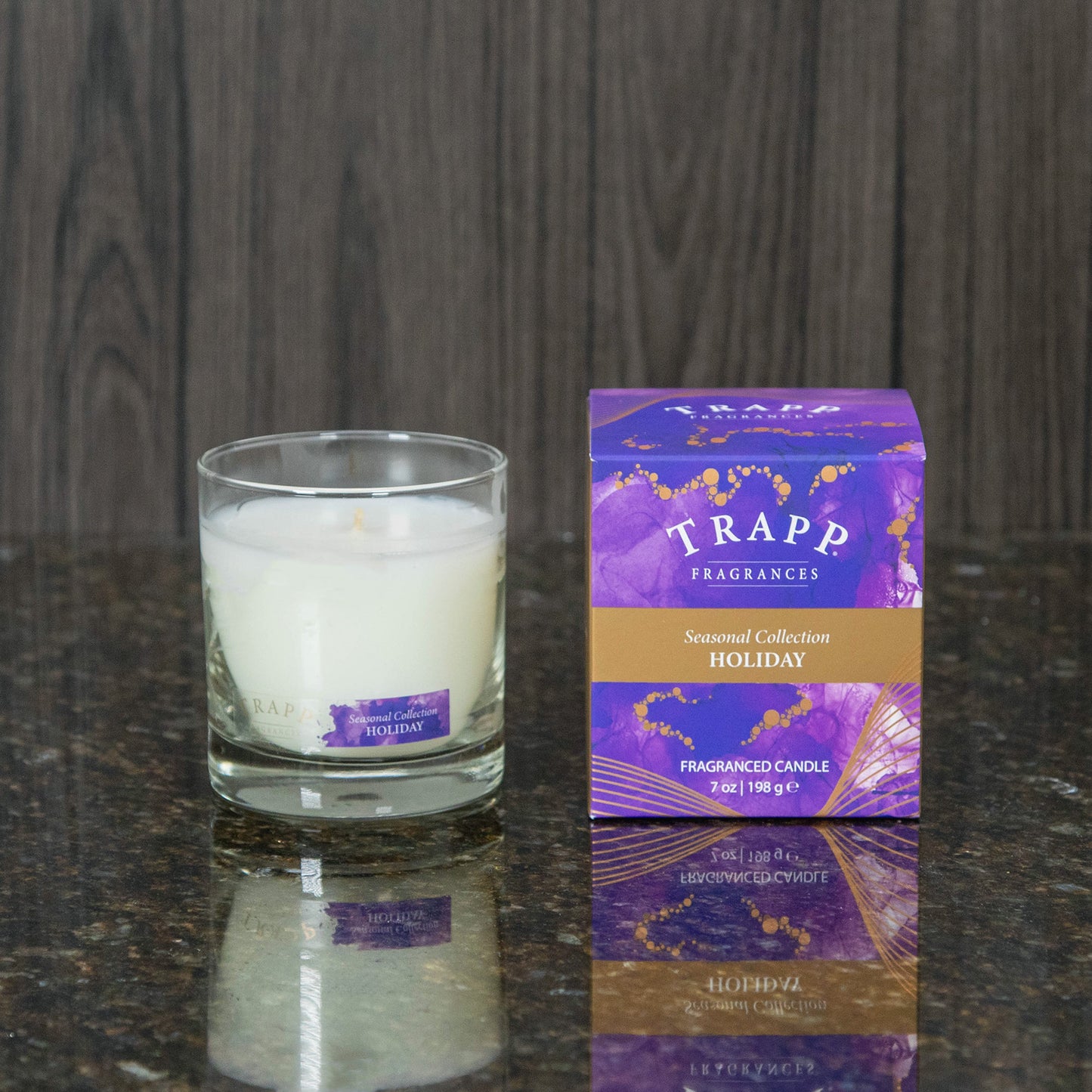 a holiday scented candle next to the purple box it comes in