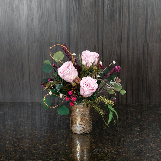 3 light pink preserved roses with dried greenery and curly willow in a gold glass cylinder vase
