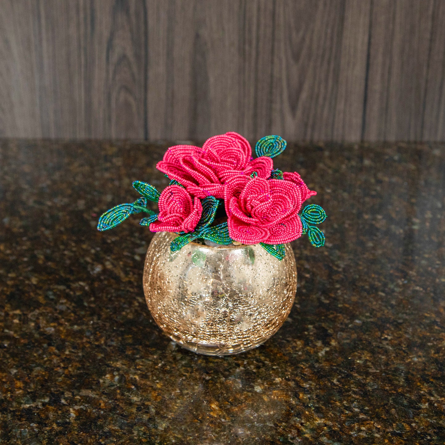 top down view of three light red french beaded roses in a gold bubble bowl vase