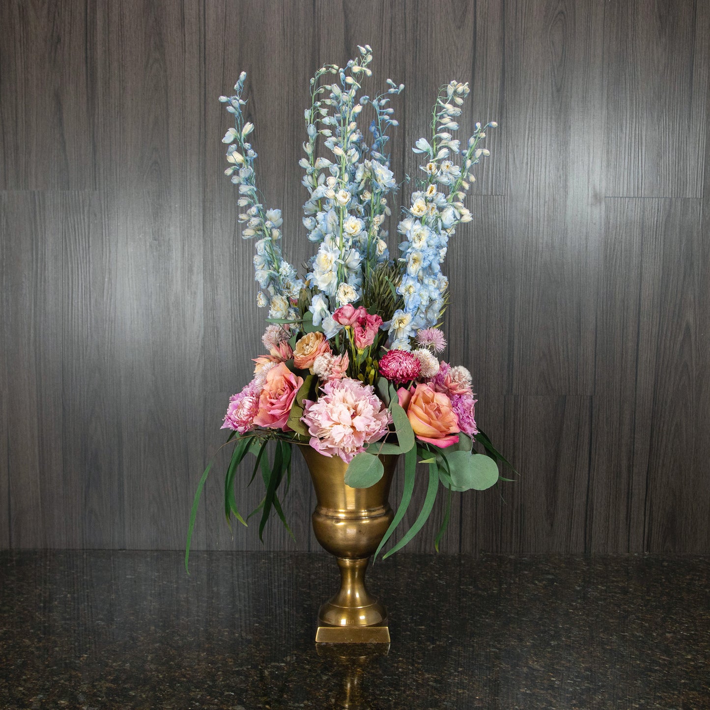a dried floral arrangement with pastel flowers in a footed metal vase