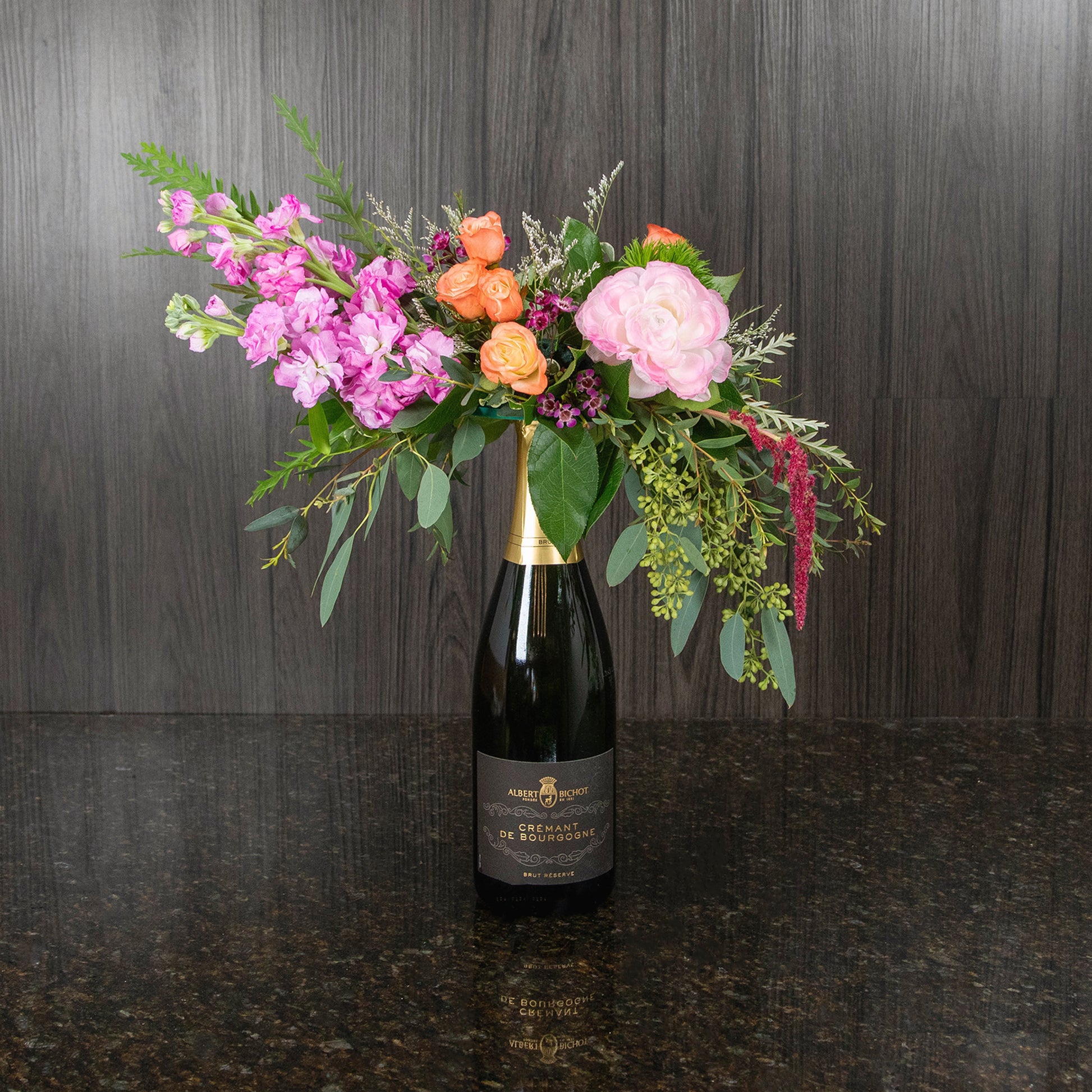 a flower arrangement on top of a bottle of champagne