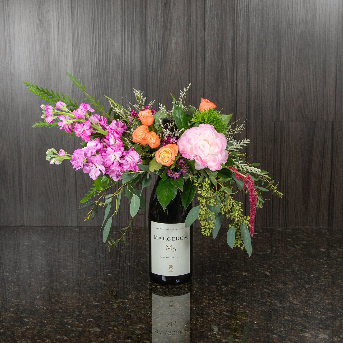 a flower arrangement on top of a bottle of red wine