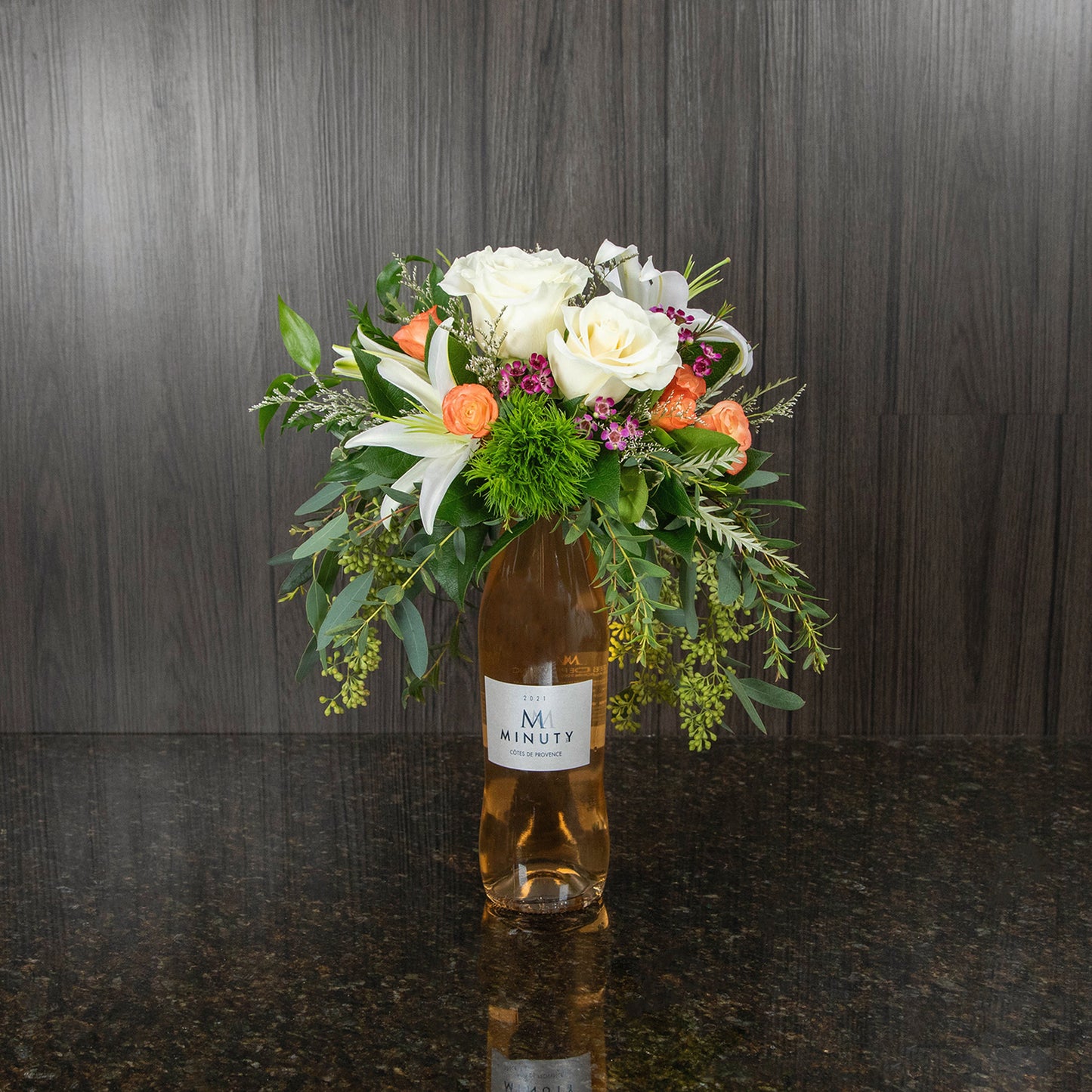 a flower arrangement on top of a bottle of rose wine