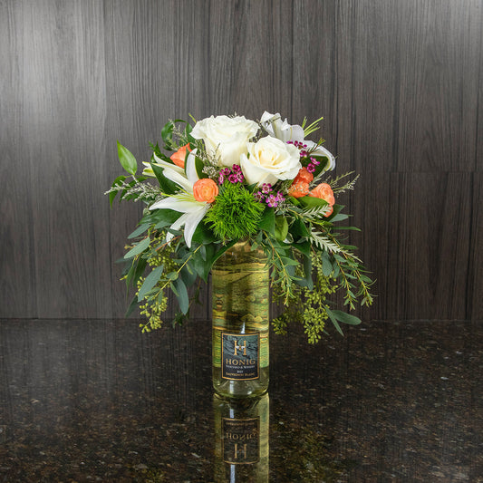 a flower arrangement on top of a bottle of sauvignon blanc
