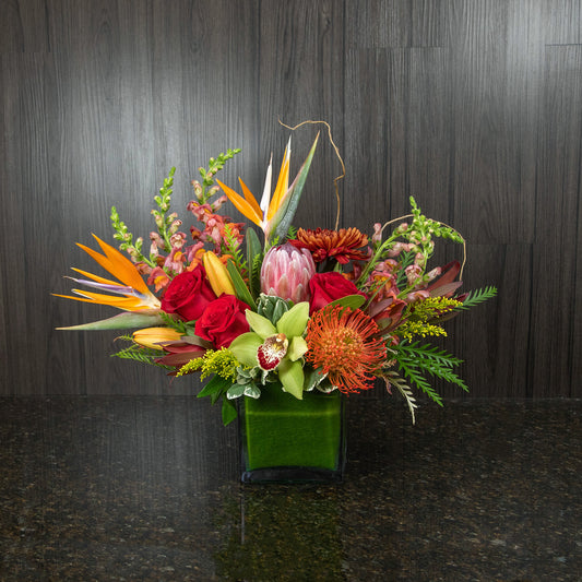 a tropical flower arrangement with a mix of warm tone flowers