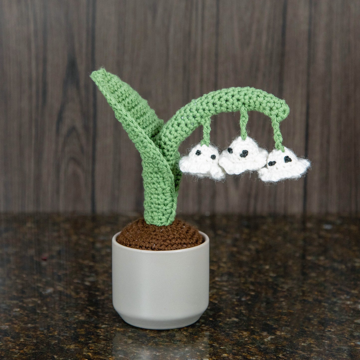 a crocheted lily of the valley plant with blooms that look like ghosts