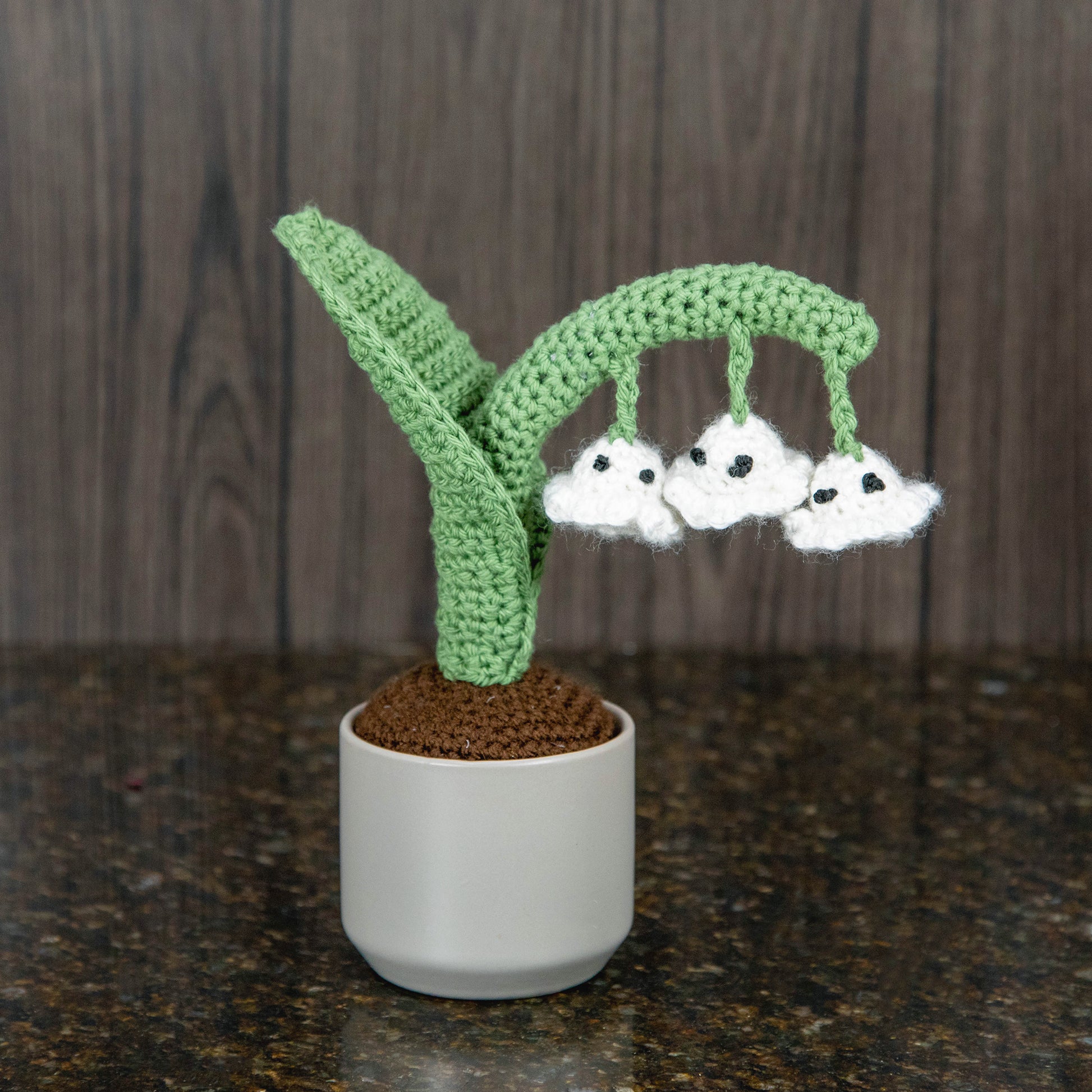 a crocheted lily of the valley plant with blooms that look like ghosts