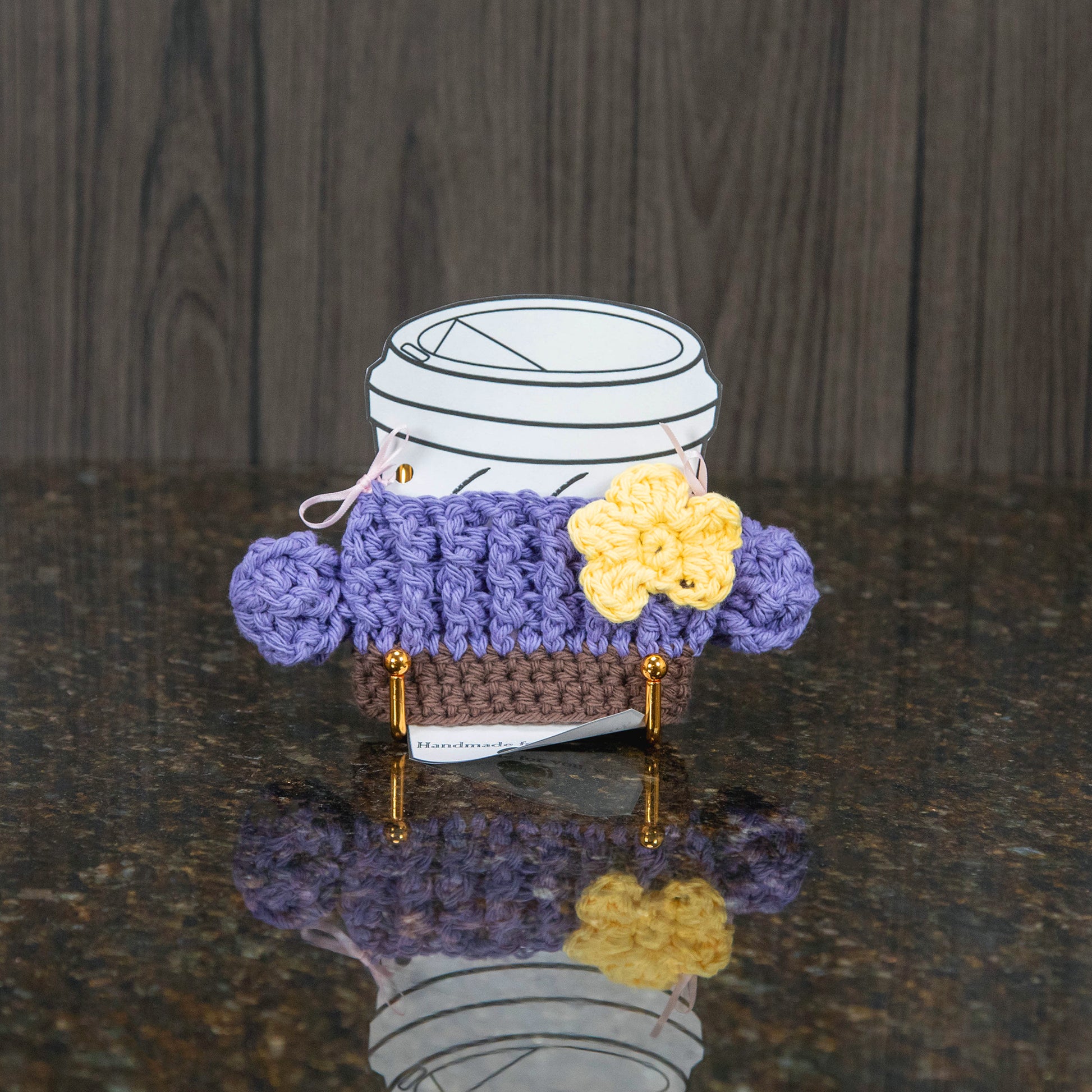 a crochet cup cozy that looks like a cactus - light purple with a yellow flower