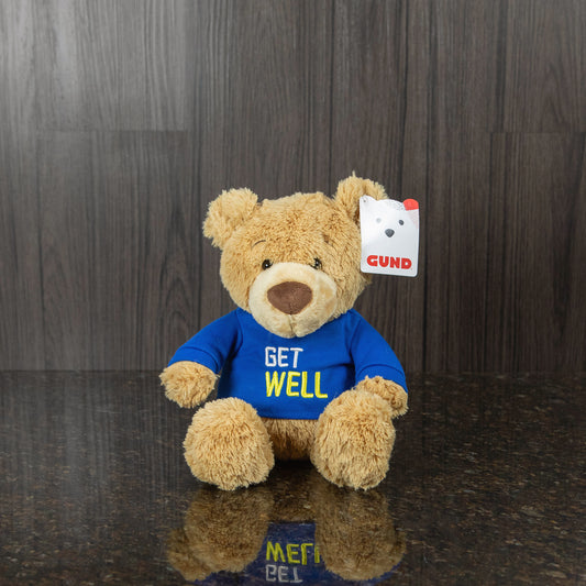 a light brown teddy bear wearing a blue shirt that reads "get well"