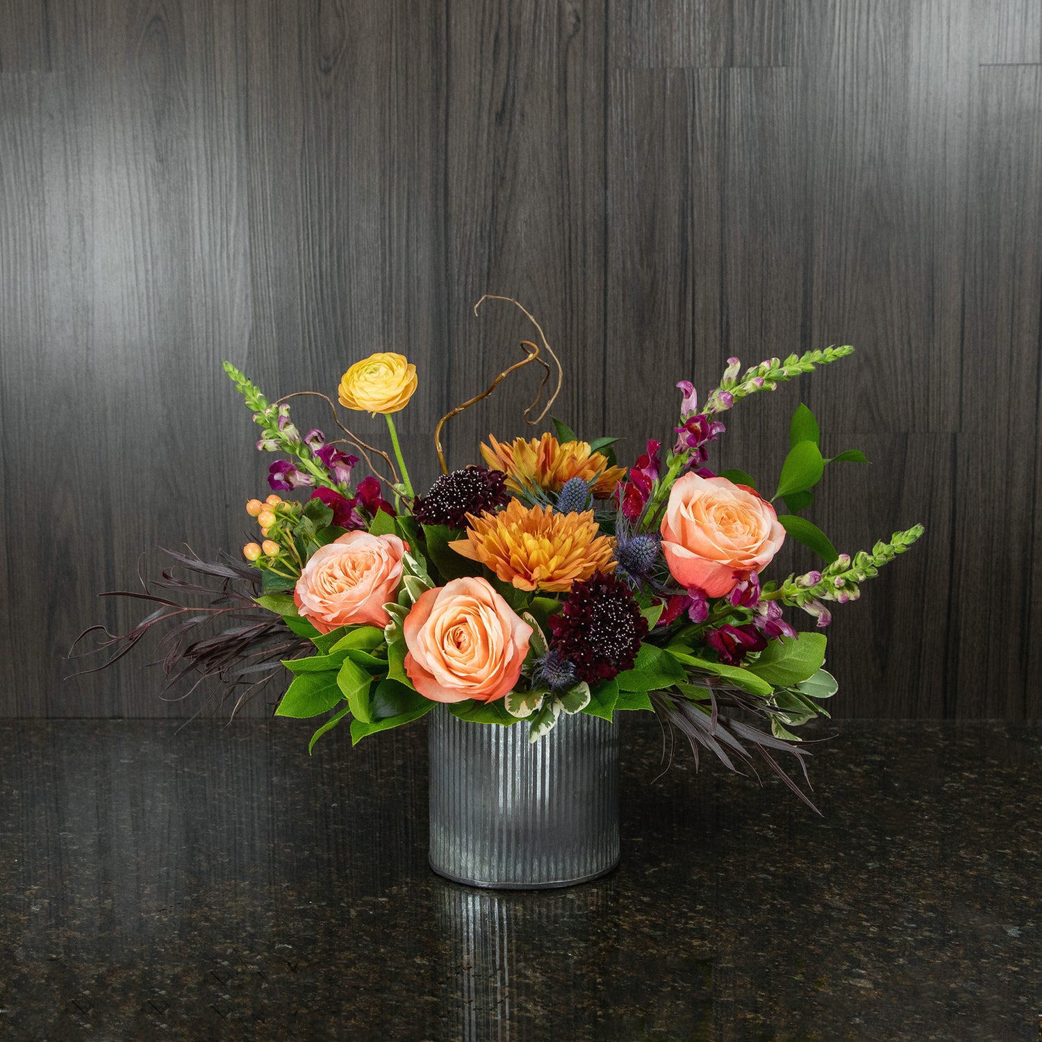 a fall flower arrangement with a mix of fall colors in a rustic metal container