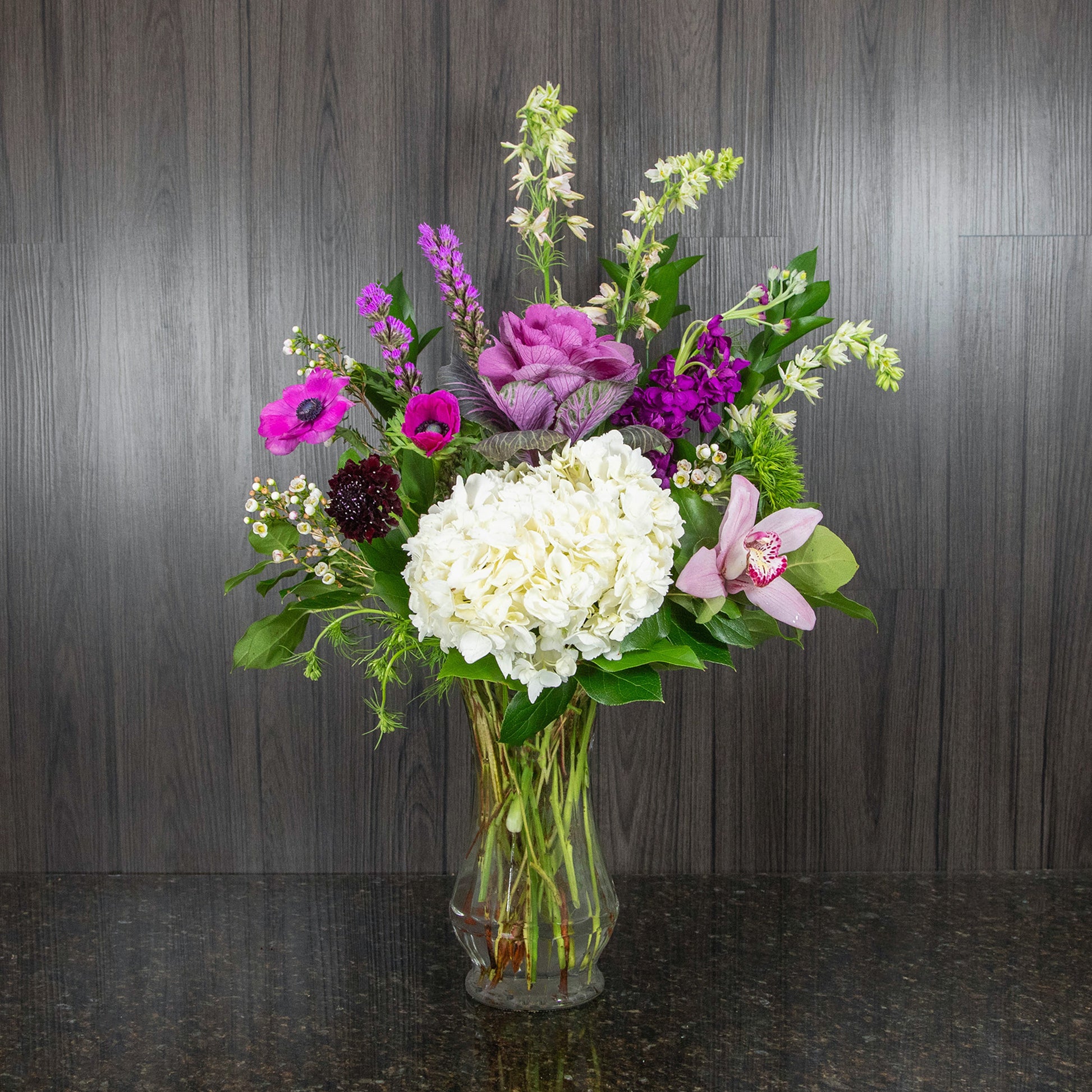 a tall flower arrangement with a mix of gardeny flowers