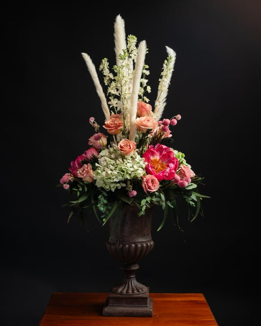 large dried flower arrangement with a mix of different types of flowers in a large footed container
