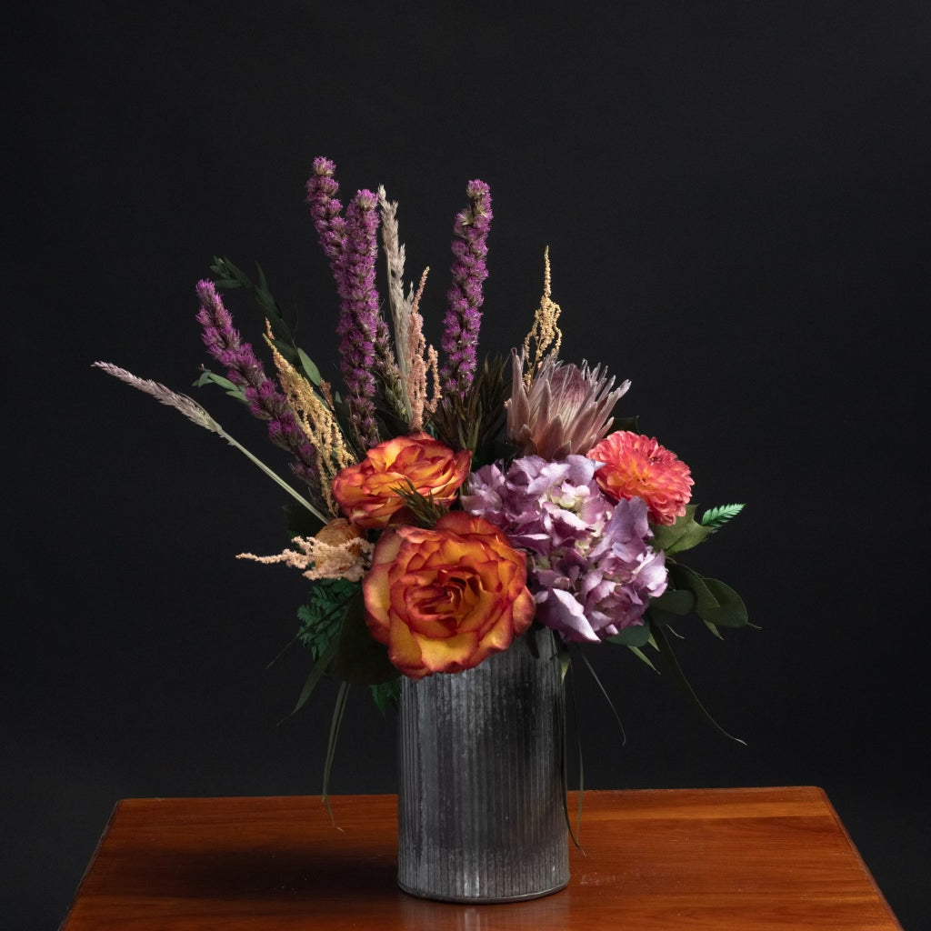 a mix of colorful dried flowers in a rustic metal corrugated vase