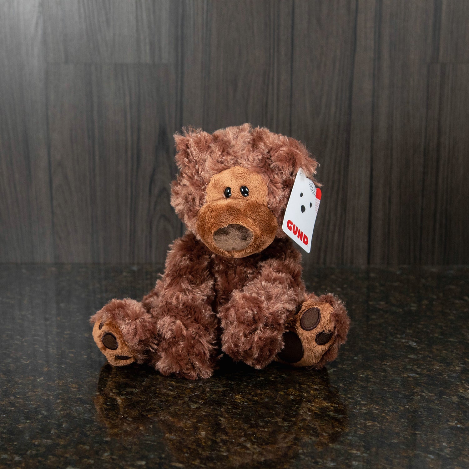 a chocolate brown teddy bear with a big nose and eyes that are intentionally a little lopsided