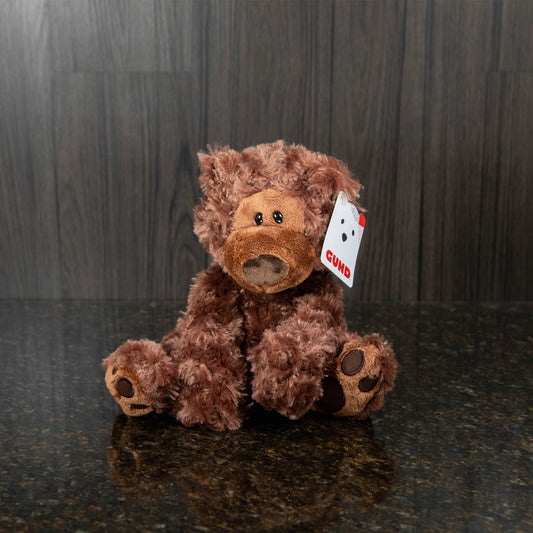 a chocolate brown teddy bear with a big nose and eyes that are intentionally a little lopsided