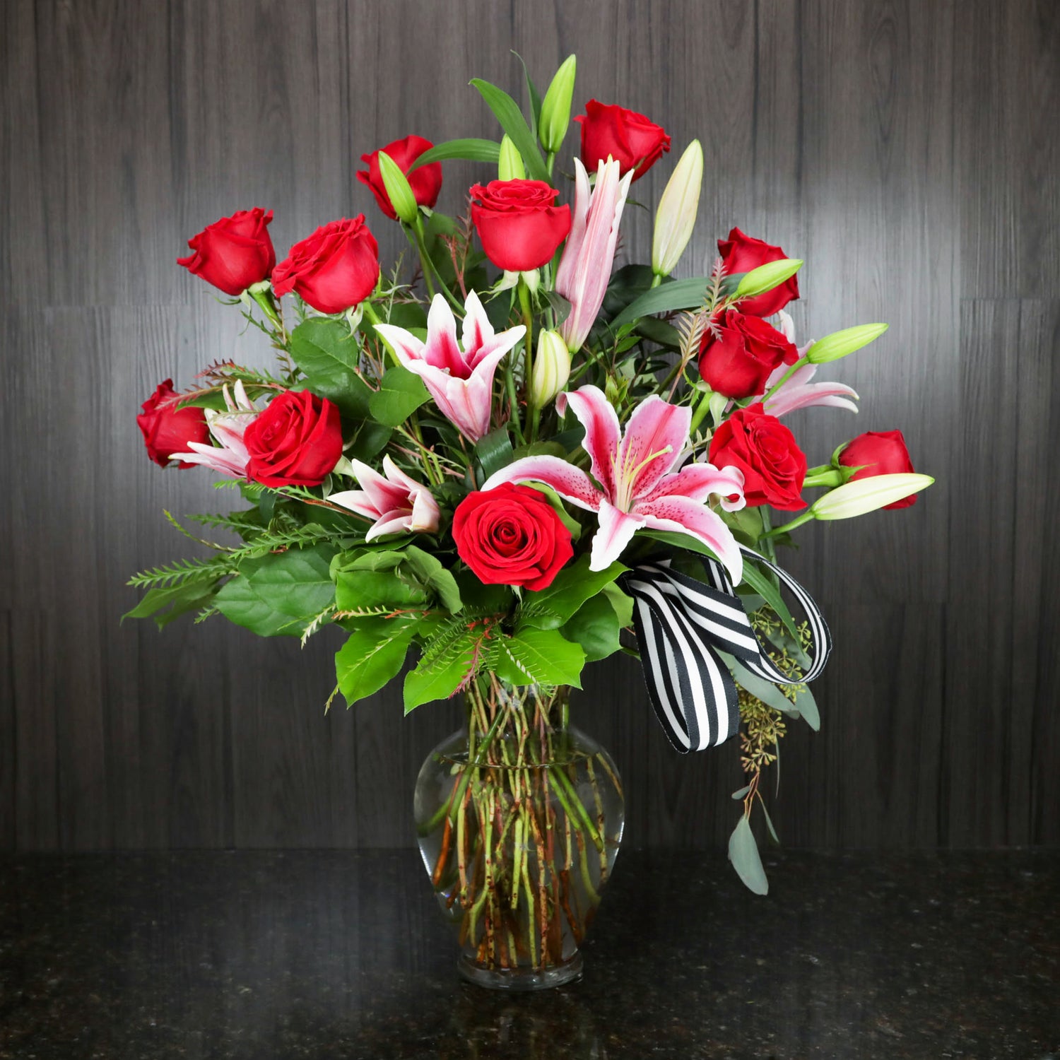 a large flower arrangement with twelve red roses and pink and white stargazer lilies