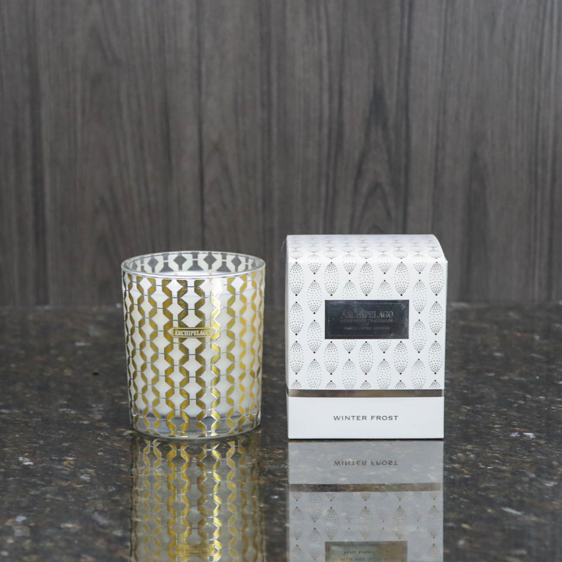 a decorative glass candle votive next to the white box it comes packaged in