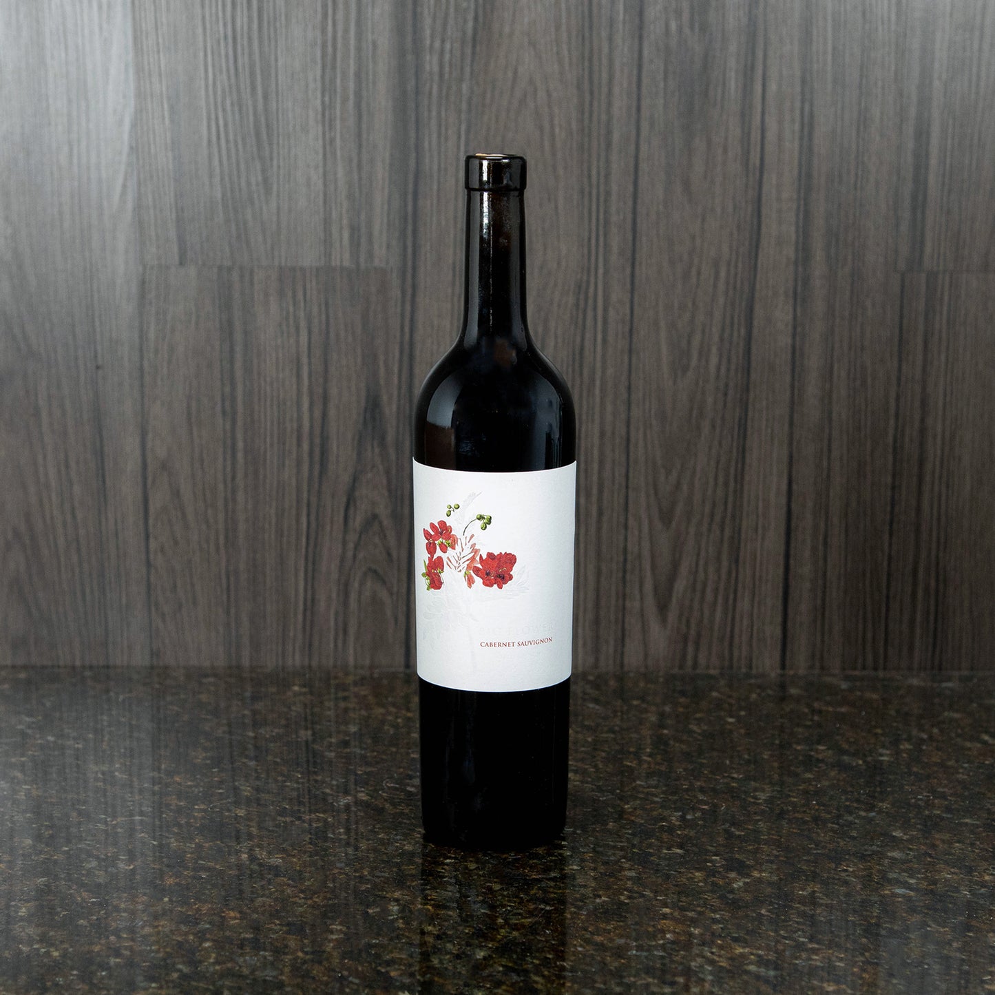 a bottle of wine with a white label that has red flowers on the side