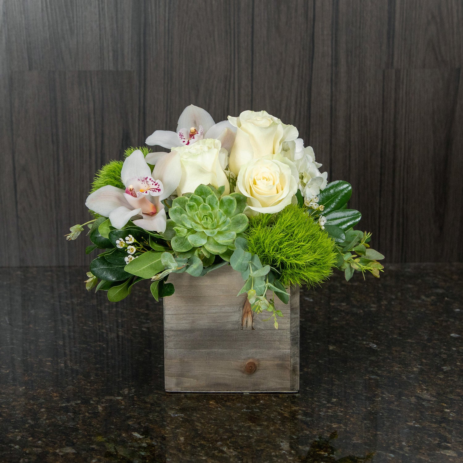 a compact flower arrangement with white and green flowers and a succulent in a wood box