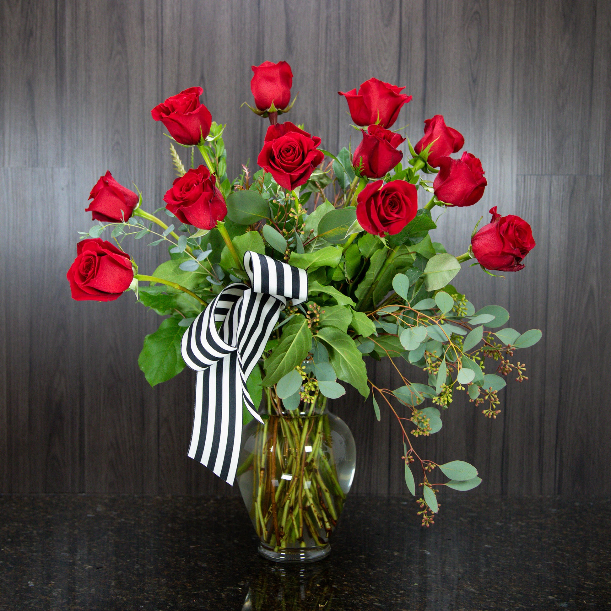 a large display of a dozen red roses in a glass vase
