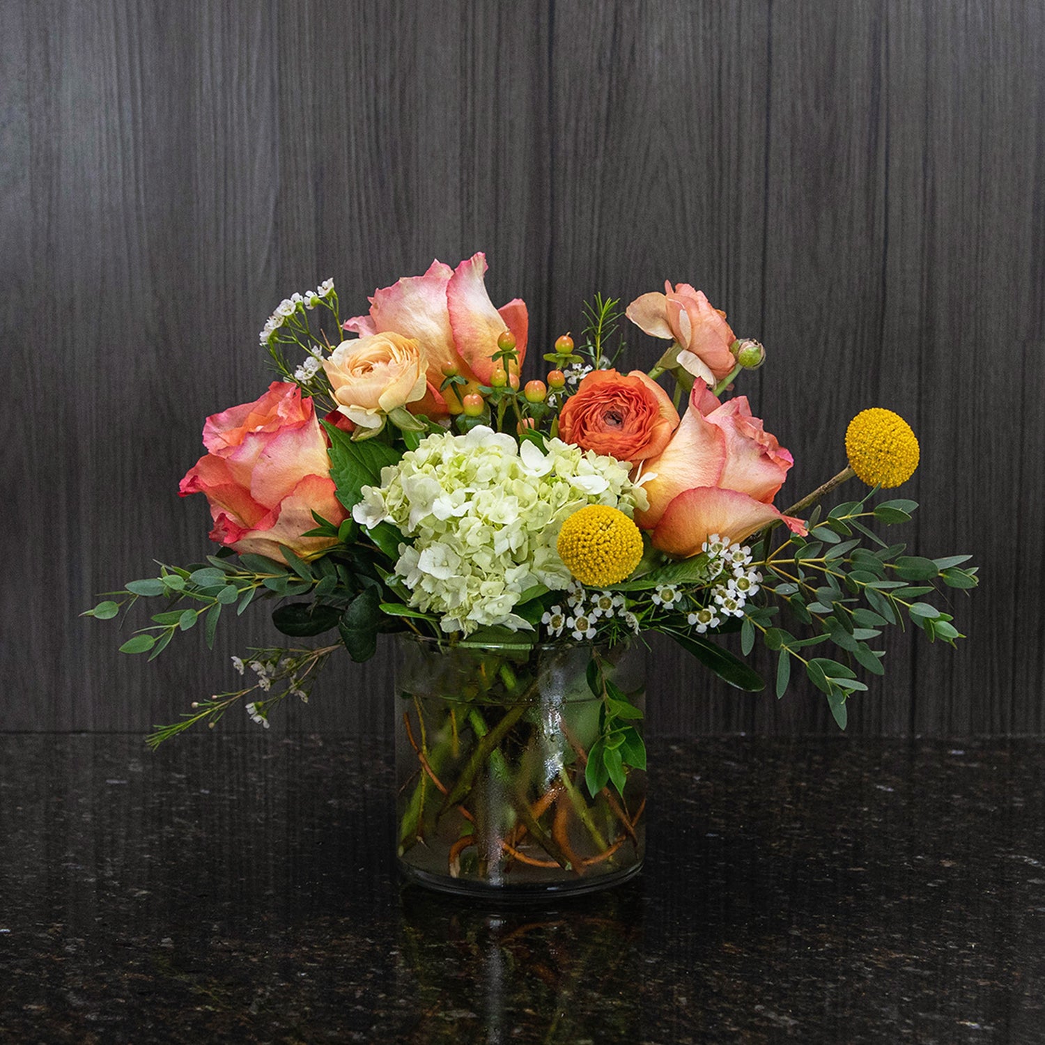 a garden style flower arrangement with yellow, orange, and green flowers