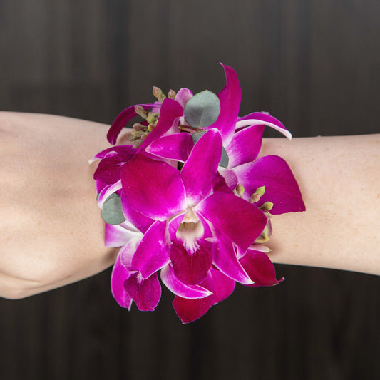 a wrist corsage with purple dendrobium orchids