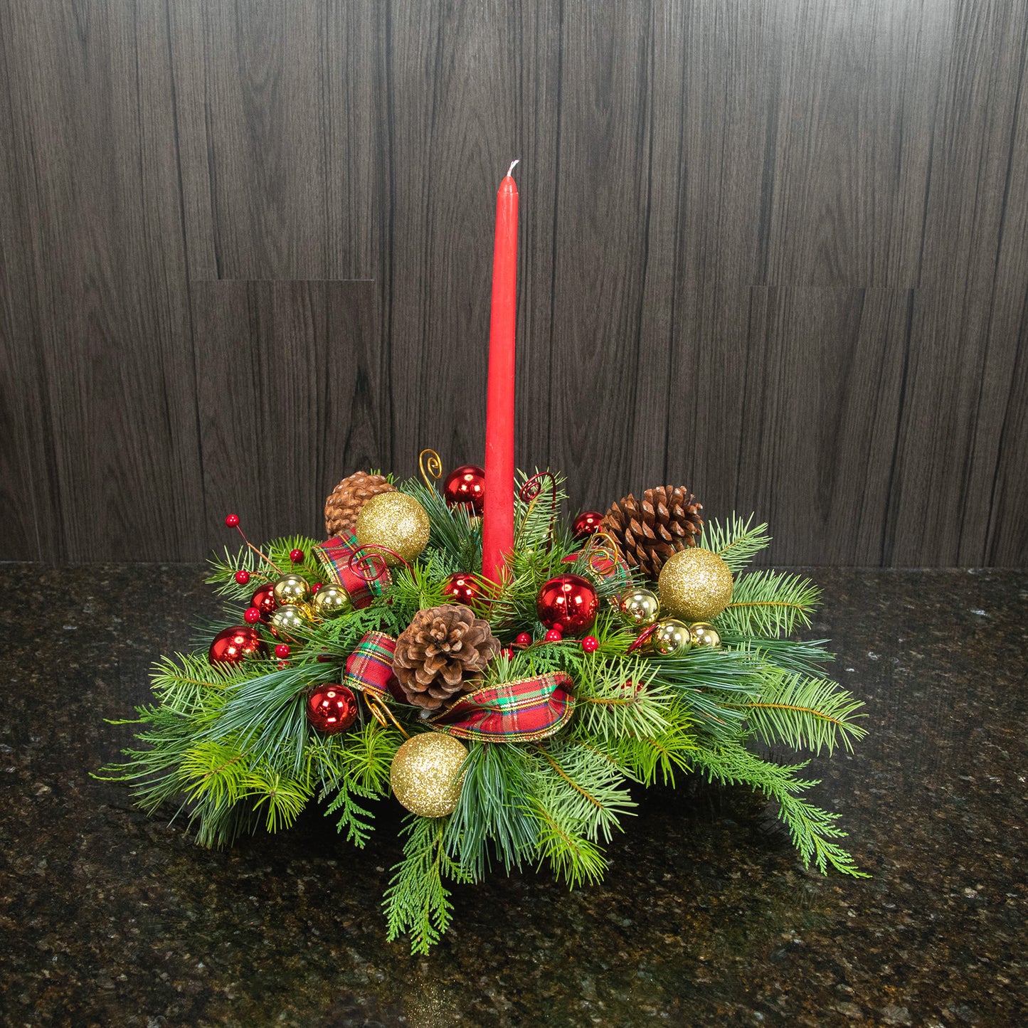 a holiday centerpiece of all pine with decorations, ribbons, and a candle