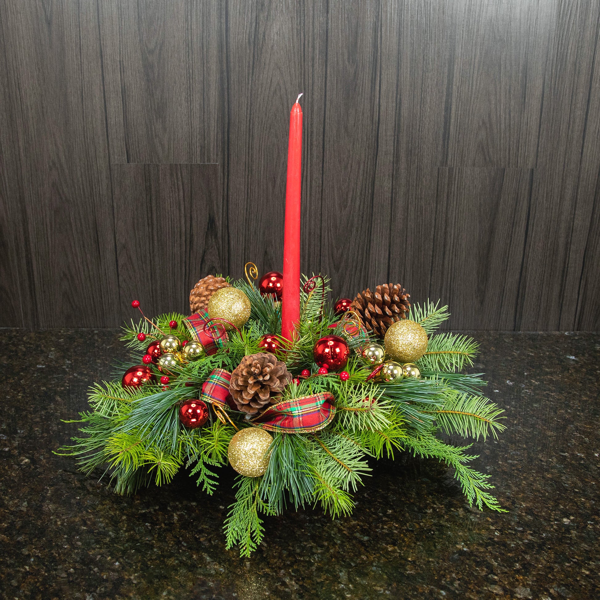 a holiday centerpiece of all pine with decorations, ribbons, and a candle
