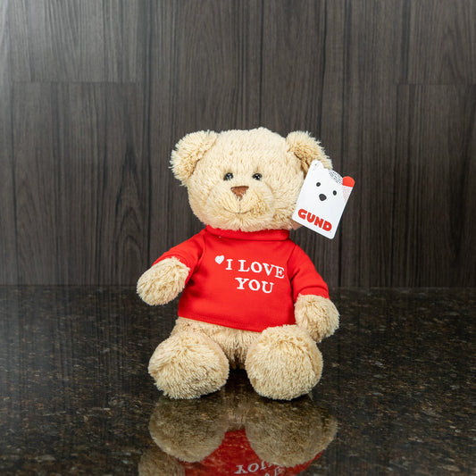 a light brown teddy bear wearing a red shirt that reads "I love you"