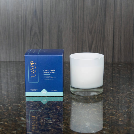 a white candle votive next to the "Coconut Blossom" box