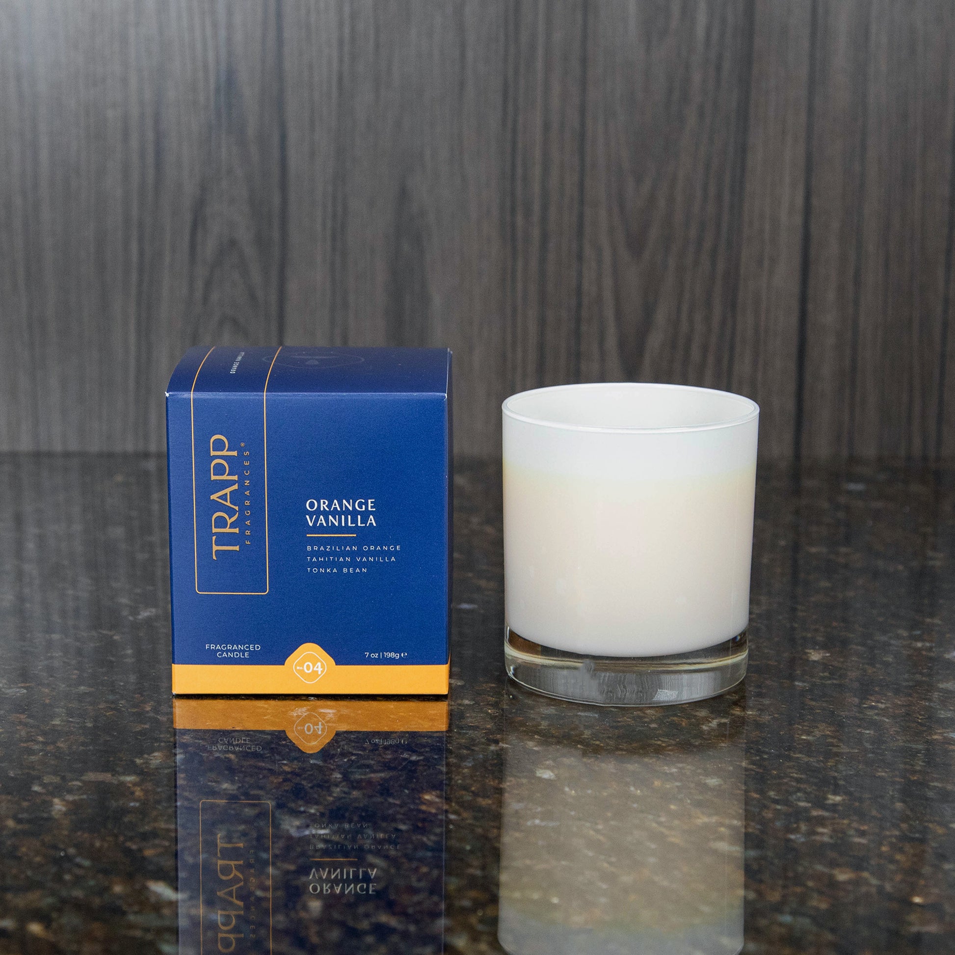 a white candle votive next to the "Orange Vanilla" box