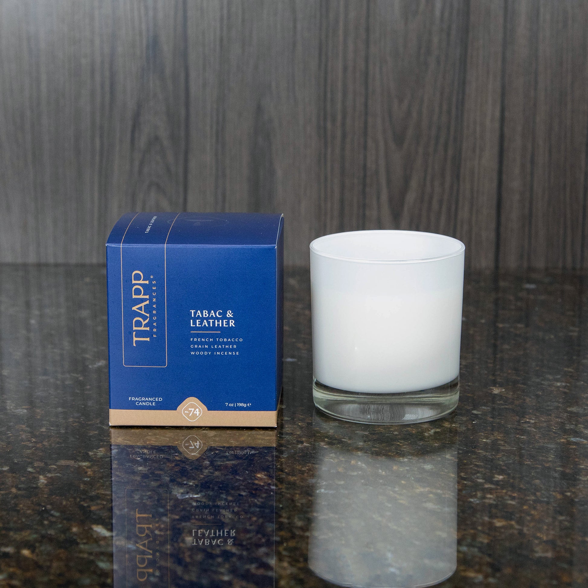 a white candle votive next to the "Tabac & Leather" box