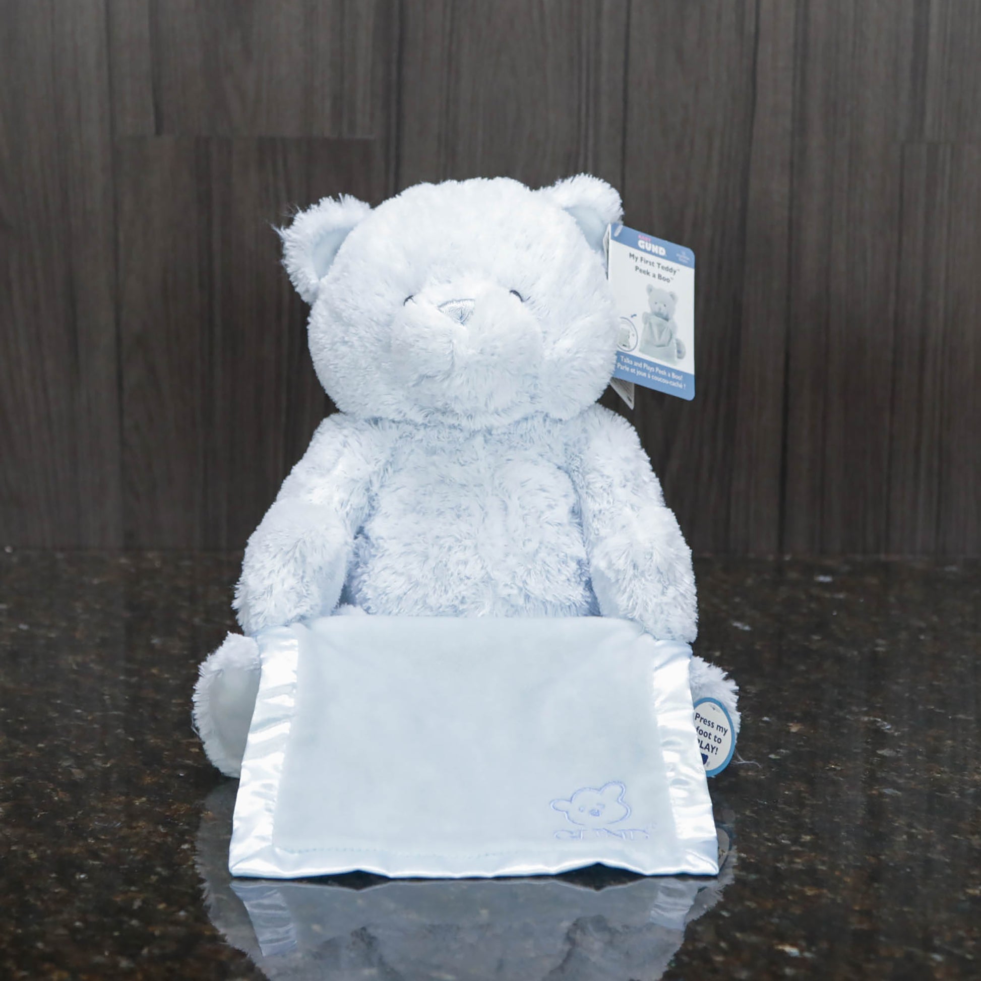 a blue teddy bear holding a blue satin blanket