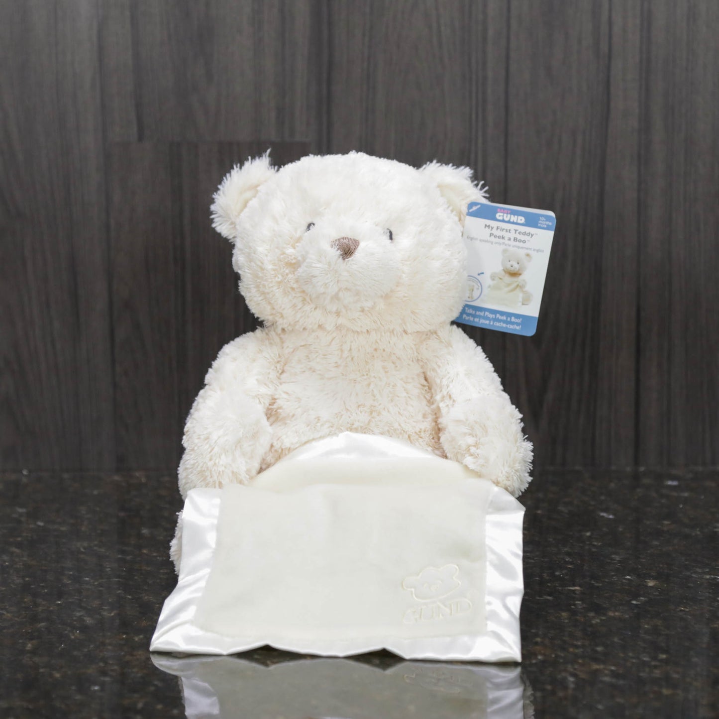 a cream teddy bear holding a blue satin blanket