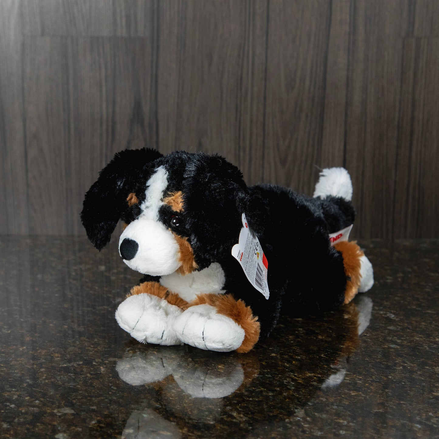 side view of a plush bernese mountain dog lying on its stomach