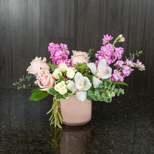 a flower arrangement with a mix of pink and white flowers in a pink ceramic vase