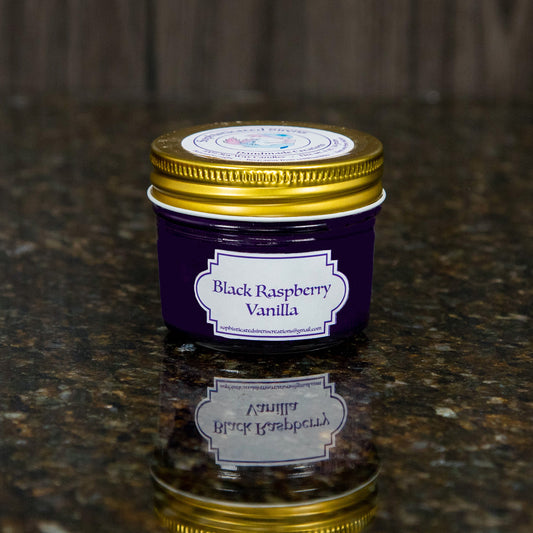 a dark purple candle with a gold lid and a label that reads "black raspberry vanilla"