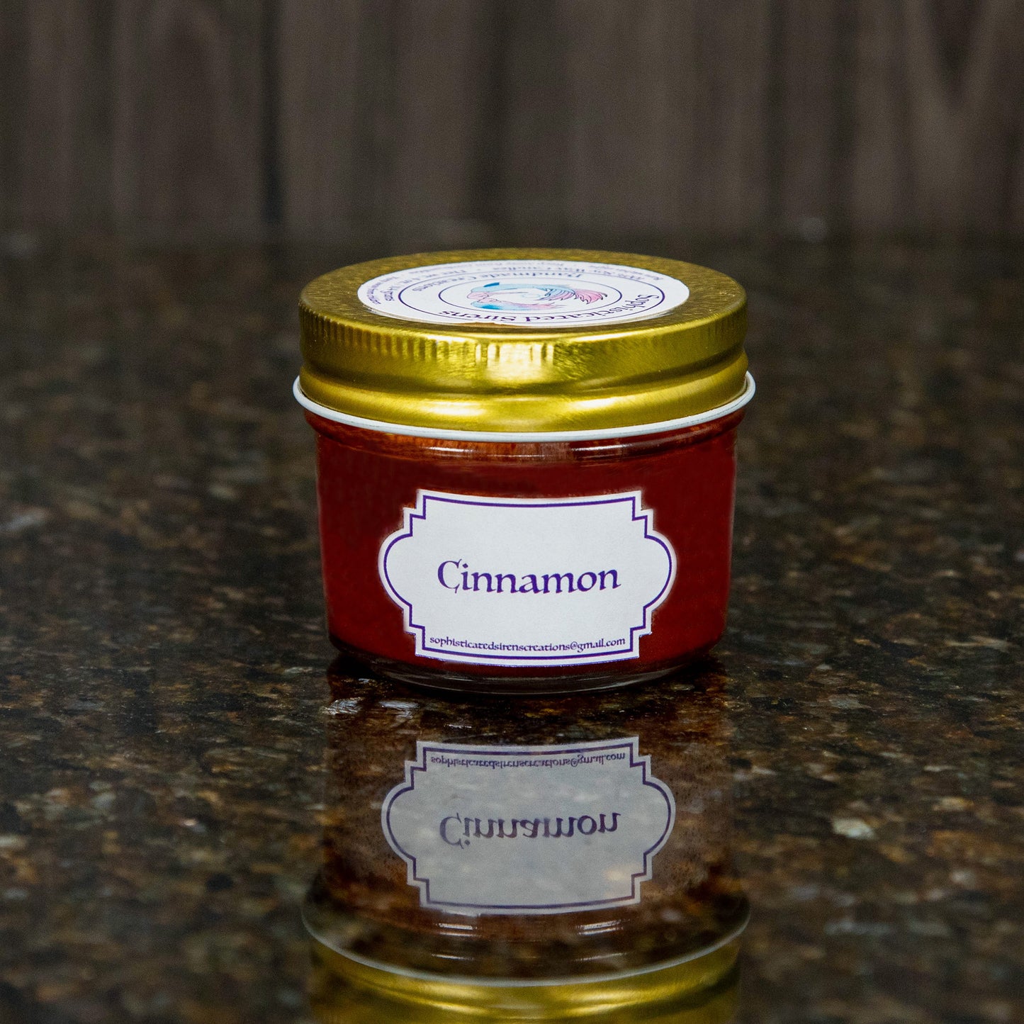 a brown candle with a gold lid and a label that reads "cinnamon"