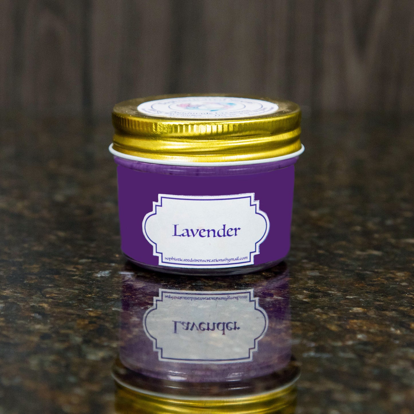 a purple candle with a gold lid and a label that reads "lavender"