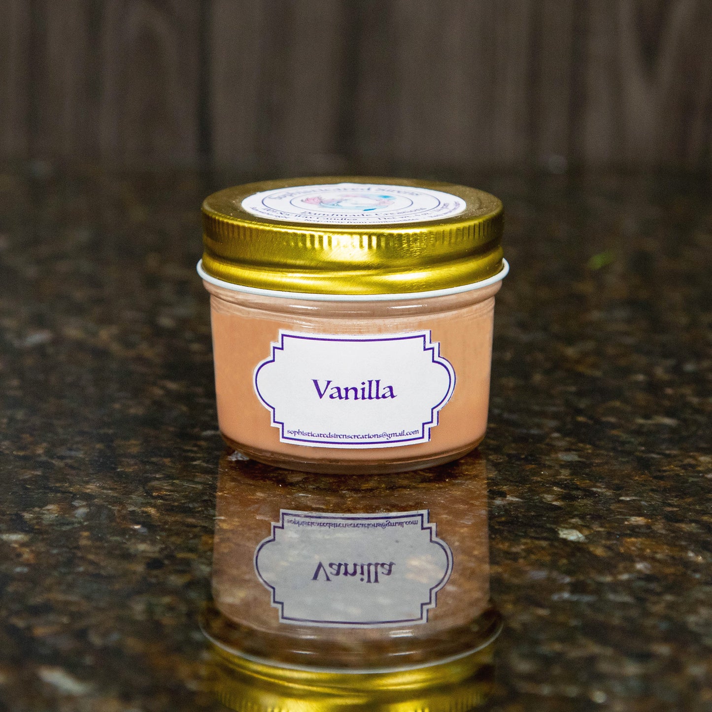 a tan candle with a gold lid and a label that reads "vanilla"