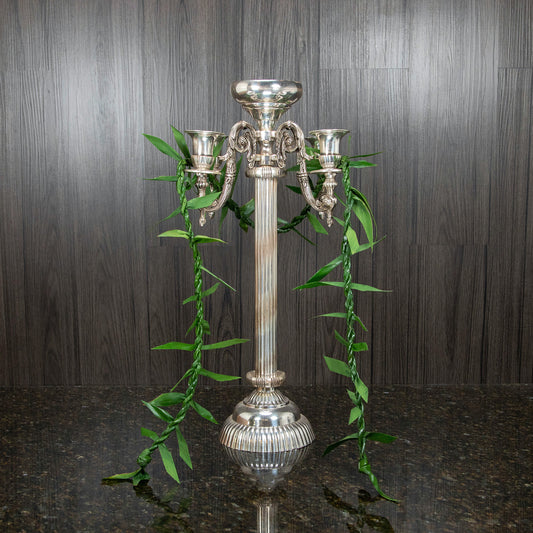 a single maile ti leaf lei hung over a silver candelabra