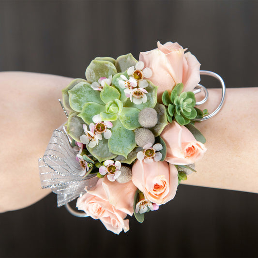 a wrist corsage made with tiny succulents and pink flowers