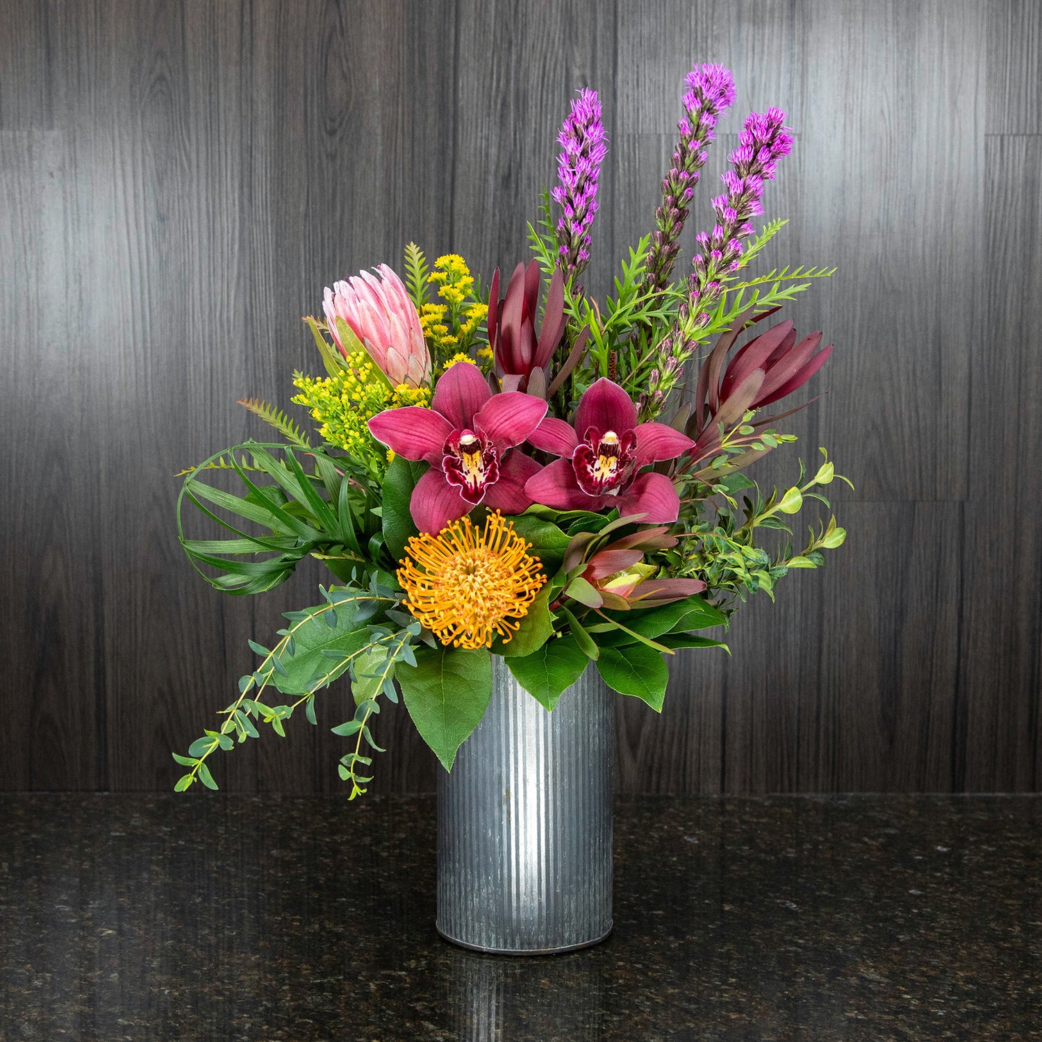 a mix of colorful tropical flowers in a metal corrugated container