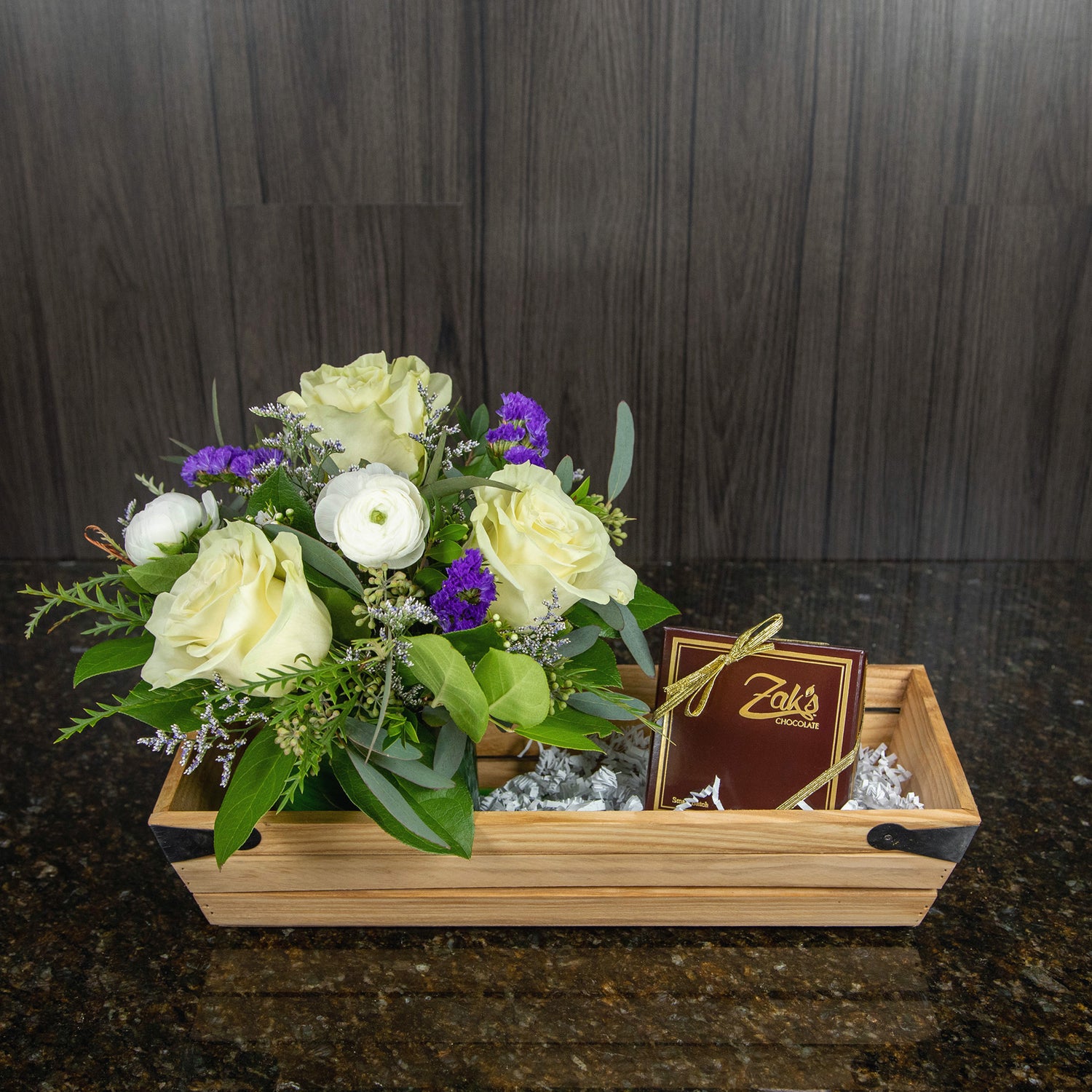 a wooden basket with a flower arrangement and a four piece box of chocolate truffles